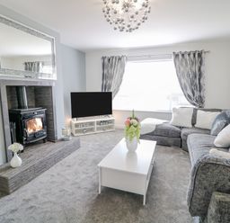A living room with sectional sofa coffee table and fireplace at SJs Cottage in Castlerock