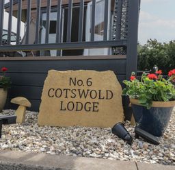 A sign stating No.6 Cotswold Lodge with flower pots in an outdoor area at The Cotswold Holiday Lodge Evesham