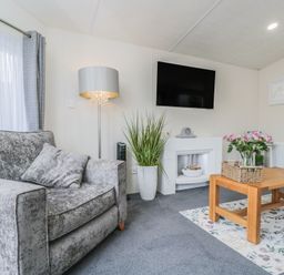 A living room with a sofa, television, and coffee table at The Cotswold Holiday Lodge in Evesham