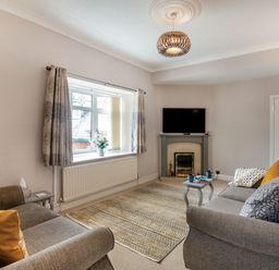 A living room with two sofas a fireplace a television and a window with curtains at Dove Cottage in Ruthin