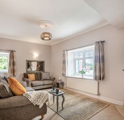 A living room with two sofas a small table a window with curtains and a fireplace at Dove Cottage in Ruthin