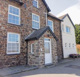 The exterior of a stone and white building with multiple windows and a small porch at Teifi Villa in St Dogmaels