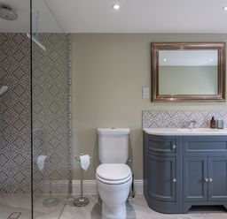 A bathroom with a toilet a grey vanity with a sink and mirror and a glass shower enclosure at Eagles Peak in Allerton near Thornton-Le-Dale