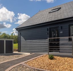 Exterior of a dark grey house with a sloped roof and a small garden area at Eagles Peak in Allerton near Thornton-Le-Dale