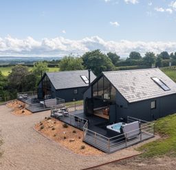 Two modern dark-colored houses with large windows and decks in a rural setting at Eagles Peak in Allerton near Thornton-Le-Dale