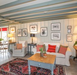 A living room with a sofa armchair wooden coffee table and dining table with chairs at Hen Beudy in Porthmadog