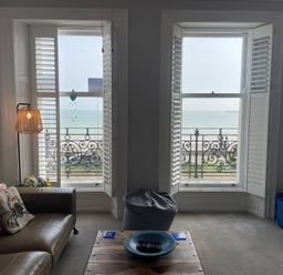 A living room with a sofa and a view of the sea at Sunrise Apartment in Weymouth