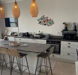 A kitchen with a large island and bar stools at Sunrise Apartment in Weymouth