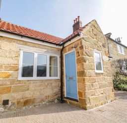 Exterior of a stone house with a blue door and white windows and a tiled roof at Rose Cottage in Faceby near Swainby