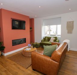 A living room with a brown leather sofa green armchair coffee table and wall mounted TV at Aran in Beddgelert