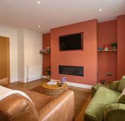 A living room with a wall-mounted television above a fireplace and green and brown sofas at Aran in Beddgelert