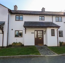 A front view of a white two story house with brown windows doors and a small porch at Craig y Llan in Beddgelert