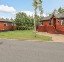 Two wooden cabins with steps and small trees on a grassy plot at 4 The Oaks in Swarland