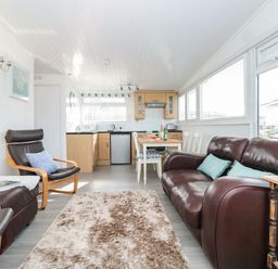 A sitting area with leather chairs and sofa next to a dining table and kitchen at Wagtails Norton near Dartmouth