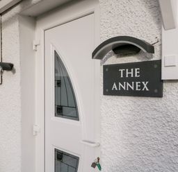 A white door with decorative glass panels and a sign reading THE ANNEX on a textured wall