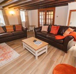 A living room with two brown sofas and a wooden coffee table at Trevedran Cottage in St Buryan