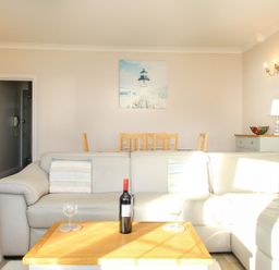 A living room with a gray sofa and wooden coffee table with a wine bottle and glasses at Ocean Watch 5 in Greenhill
