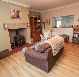A living room with a fireplace sofa armchair wooden cabinets and bookshelves at Castle Keep in Norham