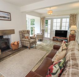 A living room with a fireplace and sofa at The Old Post House at Low Stott Park