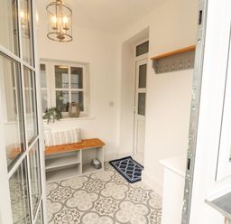 An entrance hall with a bench and coat hooks at The Old Post House at Low Stott Park