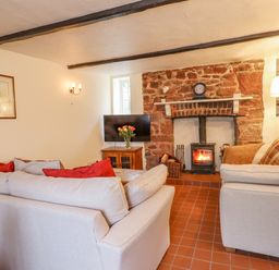A living room with two sofas a wood burning stove and a television at Rose Cottage in Holcombe in Teignmouth
