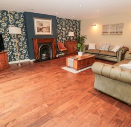 A living room with two sofas a wooden coffee table a fireplace and a television at Calm Skies in Scremerston near Berwick-Upon-Tweed