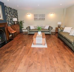 A living room with two green sofas a wooden coffee table and a fireplace at Calm Skies Scremerston near Berwick-Upon-Tweed