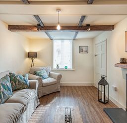 A living room with sofa armchair patterned cushions wood floor and fireplace at Smugglers Cottage in Christchurch