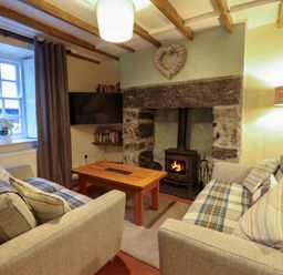 A living room with two sofas a wooden coffee table a stone fireplace with a wood stove and a heart decoration Bwthyn Y Bugail Manod near Blaenau Ffestiniog