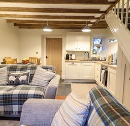 An open living room with sofas and cushions next to a kitchen and dining area at Bwthyn Y Bugail Manod near Blaenau Ffestiniog