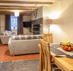 A living room with sofas a television a stone fireplace and a dining table with fruit bowl at Bwthyn Y Bugail in Manod near Blaenau Ffestiniog
