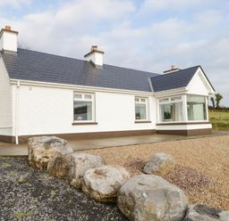 Exterior view of a white house with slate roof and large stones in front at The Water's Edge in Boyle County Roscommon