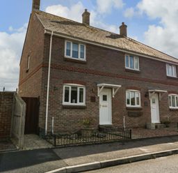 A brick semi detached house with two white front doors and small fenced garden areas at The Beach House in West Bay