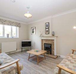 A living room with two sofas a coffee table a fireplace a floor lamp and a window at The Beach House in West Bay