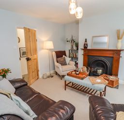 A living room with leather sofas a wooden fireplace and a coffee table at Anchor Cottage in Whitby