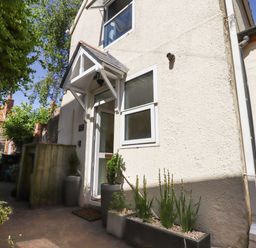 The exterior of a small house with a white door and windows and potted plants outside at Quayside Cottage in Teignmouth