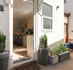 Entrance to a cottage with potted plants outside and a view into a kitchen and living area at Quayside Cottage in Teignmouth