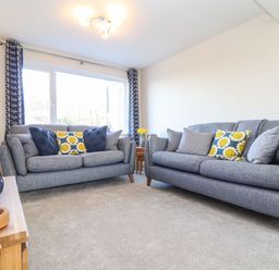 A living room with two grey sofas and patterned cushions at Pickney House Killigarth near Polperro