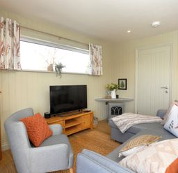 A living room with a gray sofa and armchair a wooden cabinet and a flat screen tv at The Swift in Wem