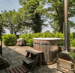 A hot tub and wooden bench with stove in the garden at Acorn in Bleadon