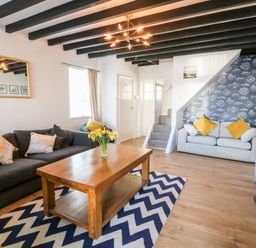 A living room with two sofas a wooden table and a patterned rug at Malltraeth Cottage in Malltraeth
