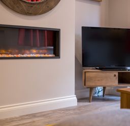 A modern electric fireplace and a flat screen television on a wooden stand in a living room at Howe Keld 1 Ground floor in Keswick