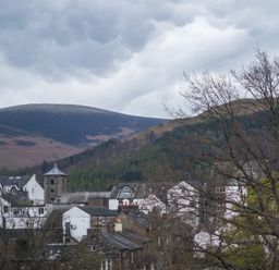 A town with houses and a stone tower with hills and cloudy sky in the background at Howe Keld 4 First floor in Keswick