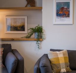 A living room with two gray sofas a plaid cushion a plant on a wooden shelf and framed pictures on the wall at Howe Keld 4 First floor in Keswick