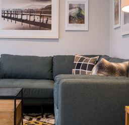 A corner sofa with cushions and framed pictures on the wall above at Howe Keld 5 First Floor in Keswick