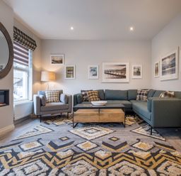 A living room with a sectional sofa armchair coffee table and wall art at Howe Keld 5 First Floor in Keswick