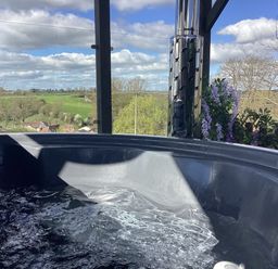 A hot tub with water and a view of fields at Cherry Pod Hookagate near Meole Brace