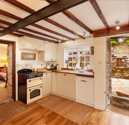 A kitchen with a stove dishwasher and wooden countertops opening to a stone patio at Southcott Farm Cottage in Sheldon