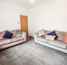 A living room with two sofas, cushions, a small table, wooden door and carpeted floor at Aryelle House in Kendal
