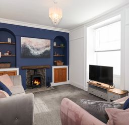 A living room with a fireplace between built in shelves sofas and a television at Aryelle House in Kendal